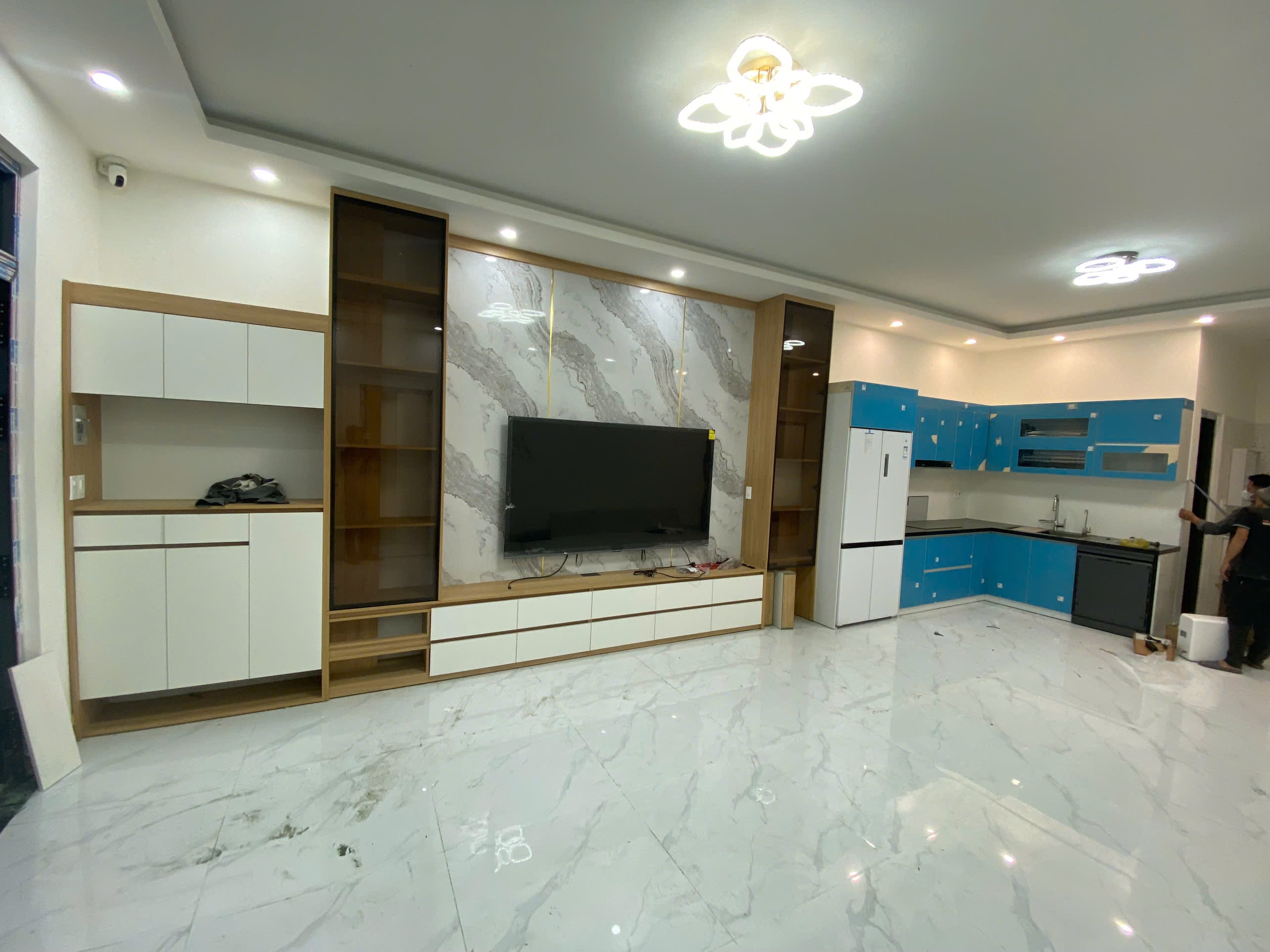 Không gian mở vách TV và tủ bếp acrylic màu xanh navy - Bếp chữ L tại Khu vực Bắc Ninh, góc nhìn 3