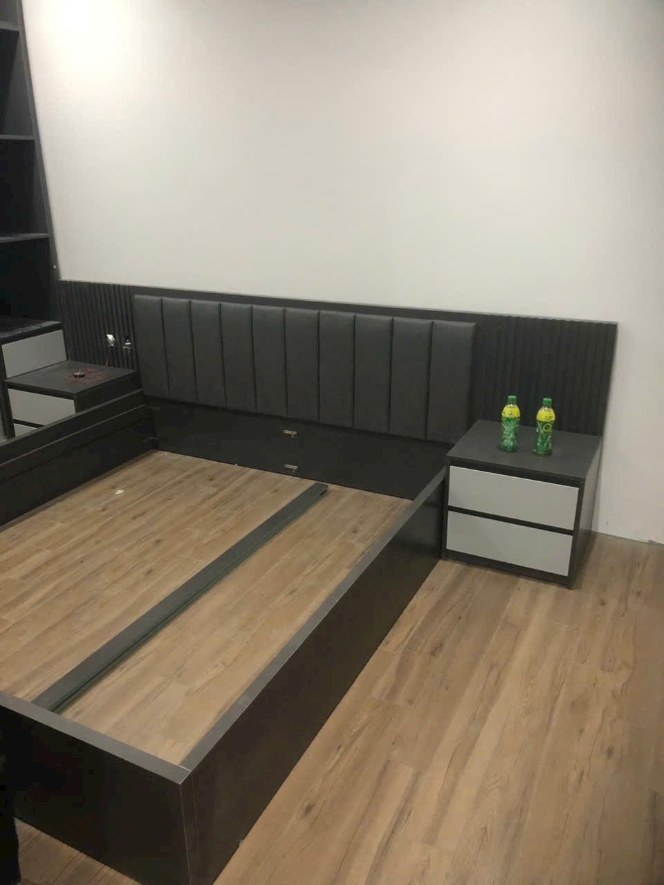 Giường ngủ gỗ MDF tựa đầu bọc đệm nỉ xám tro thanh lịch trong phòng ngủ căn hộ, góc nhìn 2