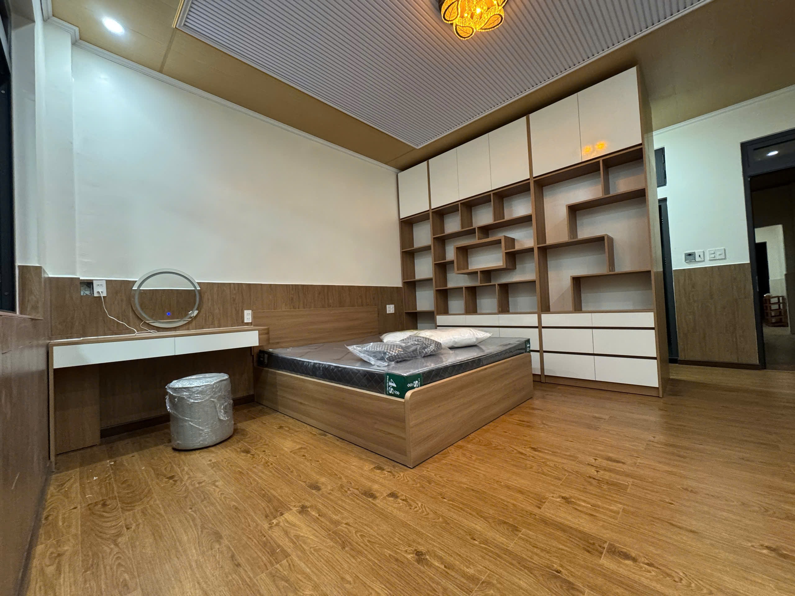 Vách ốp nan gỗ MDF trang trí đầu giường phòng master kết hợp ánh đèn LED vàng ấm, góc nhìn 3