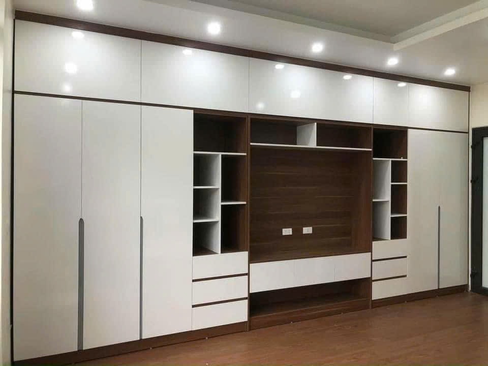 Phòng ngủ master gỗ MDF với vách nan ấm áp và hệ kệ tivi kịch trần đối diện giường, góc nhìn 2